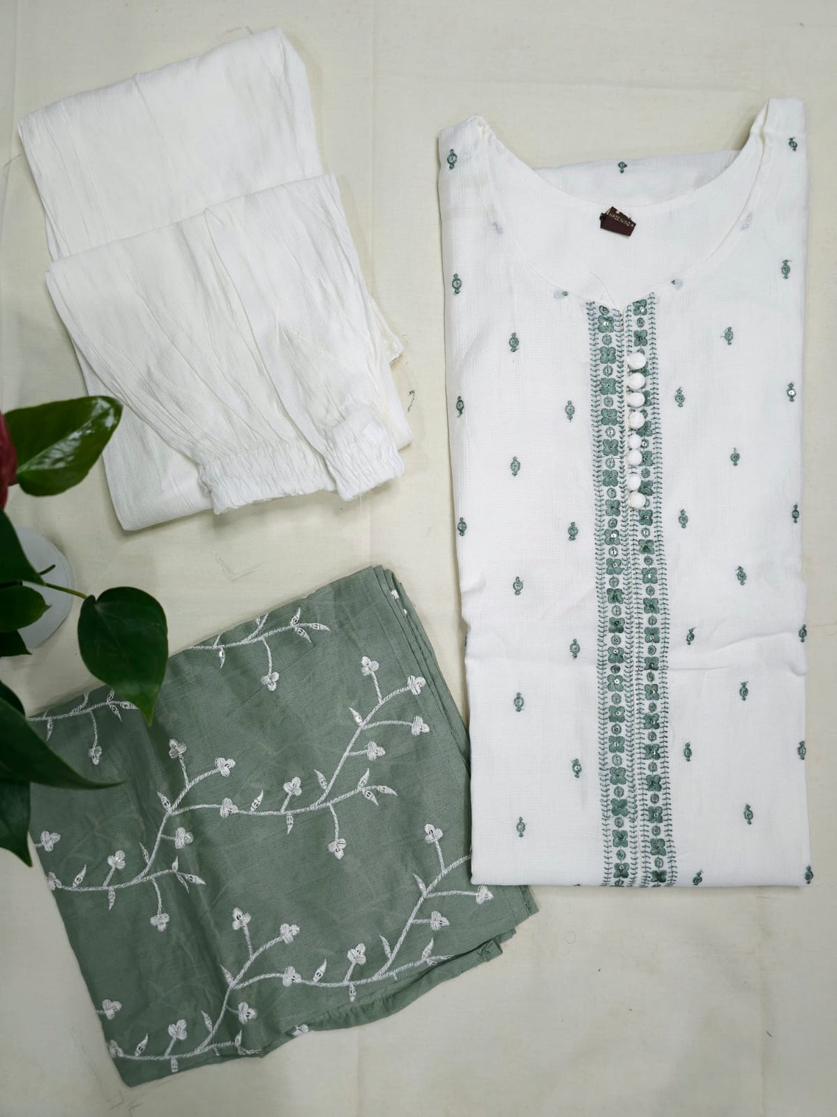 White shirt with green embroidery and green fabric with white patterns on a light background